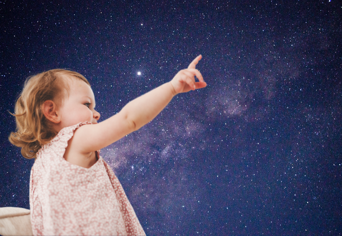 Bébé pointant le ciel étoilé de la nuit, symbolisant l’astrologie et le thème astral personnalisé.